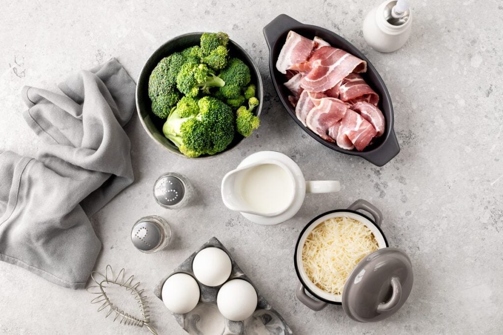 Brokkoli, Bacon, Eier, Sahne und geriebener Käse in Schalen von oben